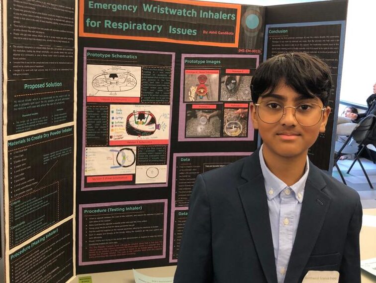 Akhil stands in front of his board at a science fair.